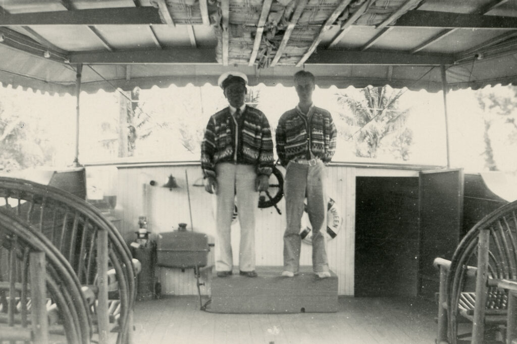 Historic photo of owner and guest at helm of Jungle Queen